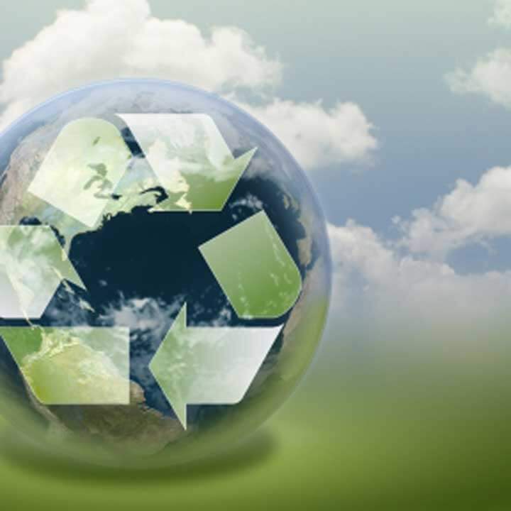 Abstract recycling logo on a globe with blue/cloudy sky behind globe