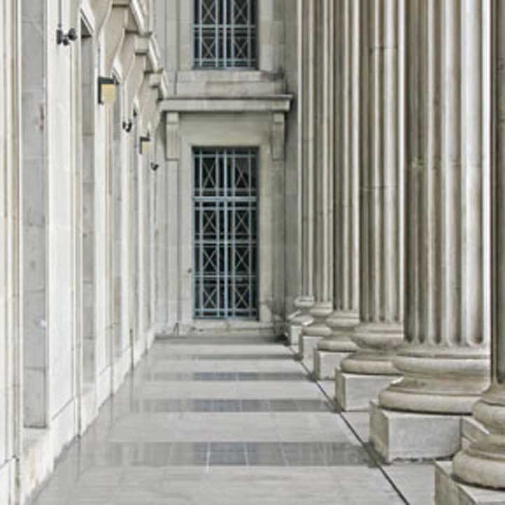 Row of white columns with a window in the distance