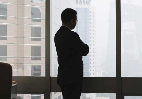 silhouette of a man looking out of a skyscraper window