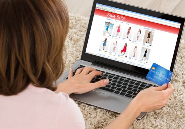 Woman Lying On Carpet Shopping Online On Laptop With Debit Card
