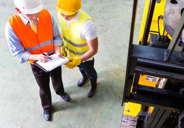 fork lift truck driver discussing checklist with foreman in warehouse