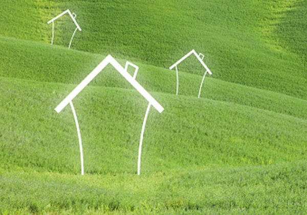 Abstract houses on green meadow landscape