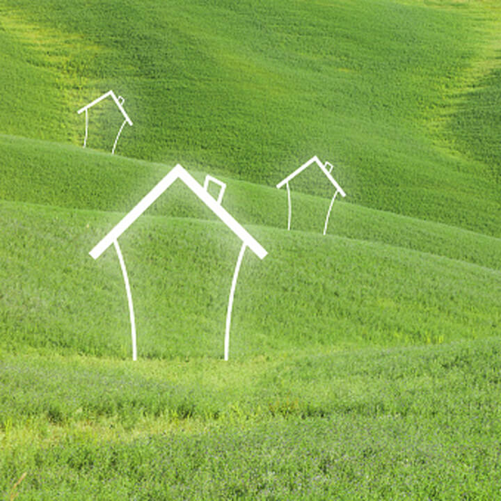 Abstract houses on green meadow landscape