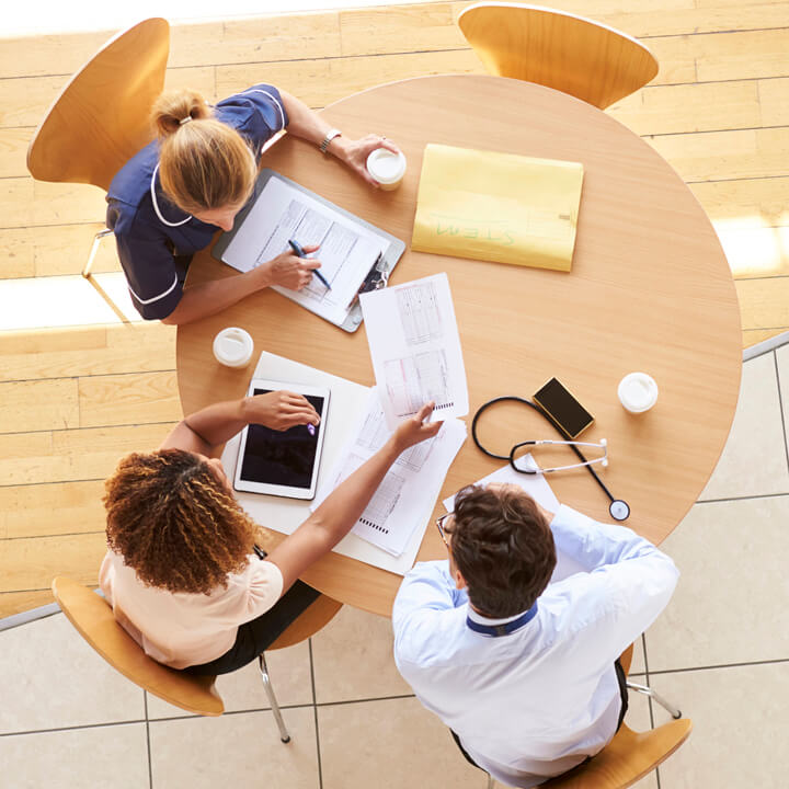 Three senior healthcare workers in a meeting, overhead view