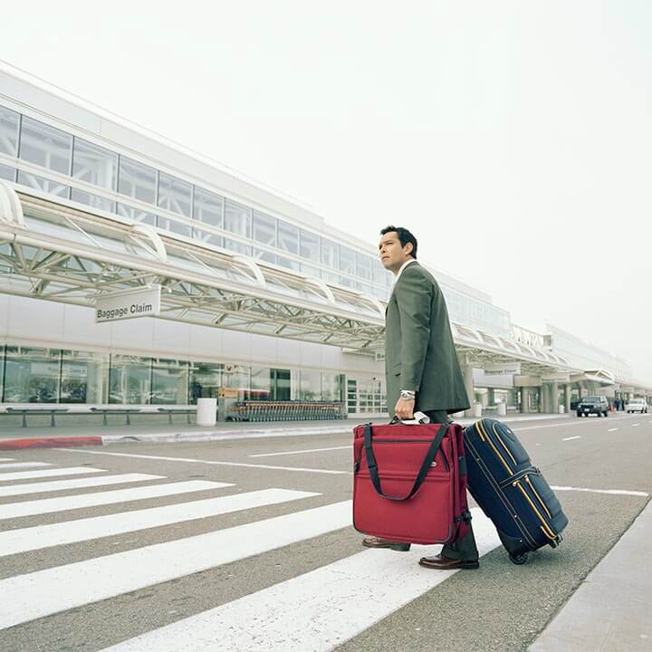 Businessman with luggages crossing road to airport