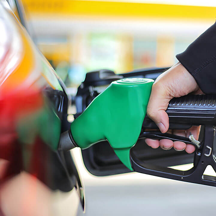 Close up hand holding fuel nozzle and being fill gas tank of black car