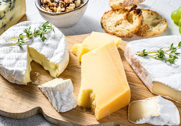 Assorted-cheeses-on-a-wooden-cutting-Board.-Camembert-brie-Parmesan-and-blue-cheese-with-grapes-and-walnuts