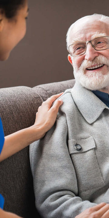 nurse touching a gentlemens shoulder before the Acute recruitment crisis in the care sector