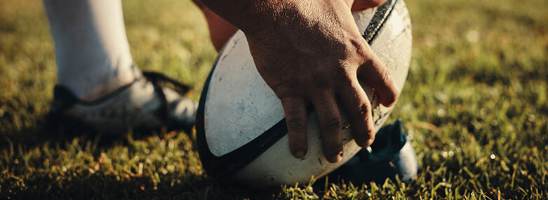 Cropped shot of an unrecognizable rugby player preparing for a kick on the field during the day
