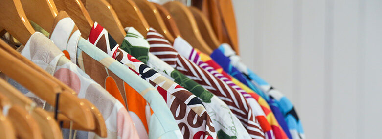 Variety-of-colorful-shirts-hanging-on-the-wooden-hangers-close-up