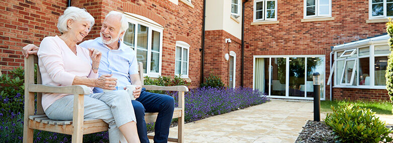 Retired-Couple-Sitting-Outside-a-Retirement-Village-with-a-hot-drink-hero-image