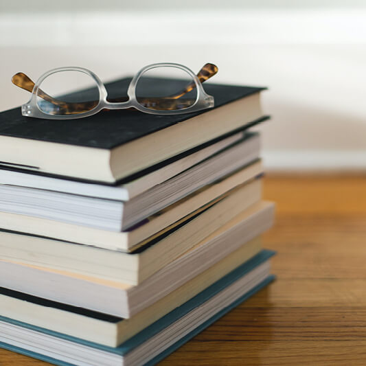 a pile of books on a table with glasses
