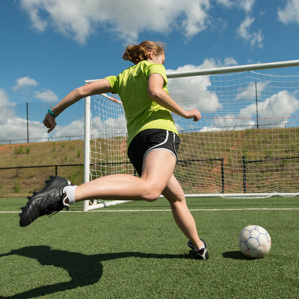 Women playing football shooting a penalty towards goal