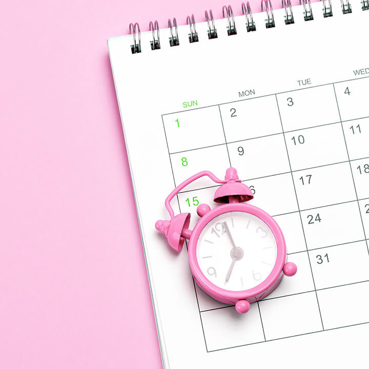 Pink-alarm-clock-and-calendar-on-a-pink-background.-Concept-days-of-menstruation-or-menopause