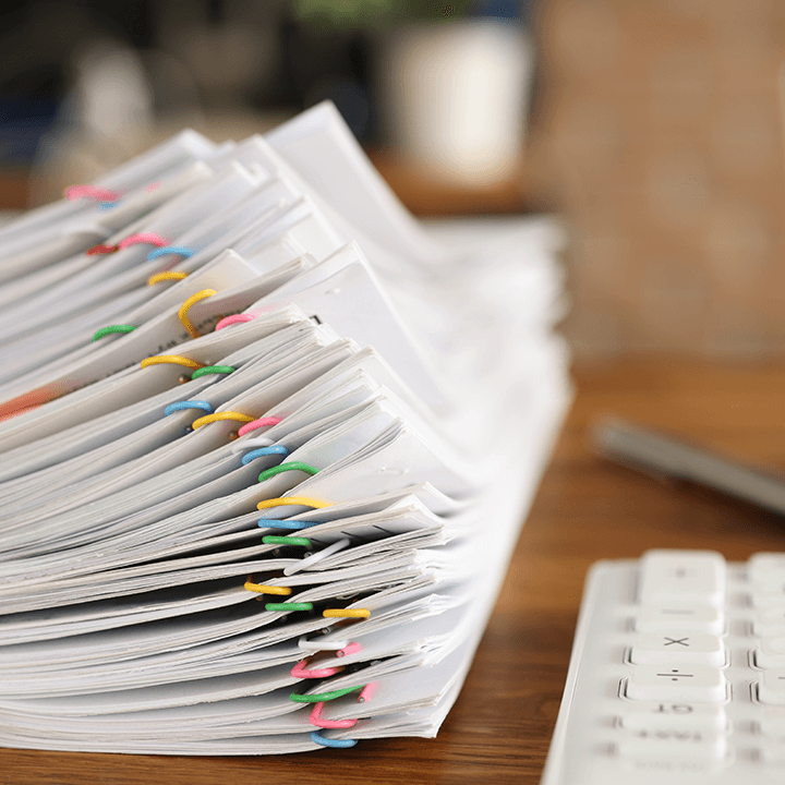 Pile-of-documents-with-paper-clips-next-to-keyboard