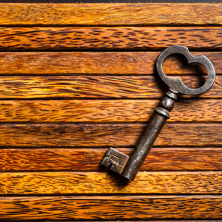 An image of an old key, lying on a wooden table. A visual metaphor for security relevant to the topic of this article, legal privilege.