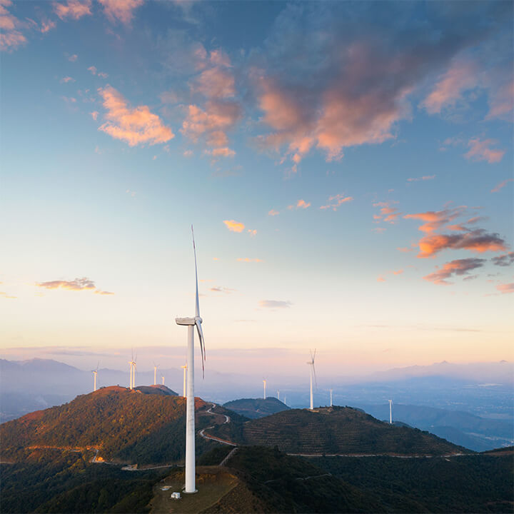 An image of a windfarm on a mountain range with a dusky sky behind. A visual metaphor for the topic of this article, the Environmental Improvement Plan 2023.