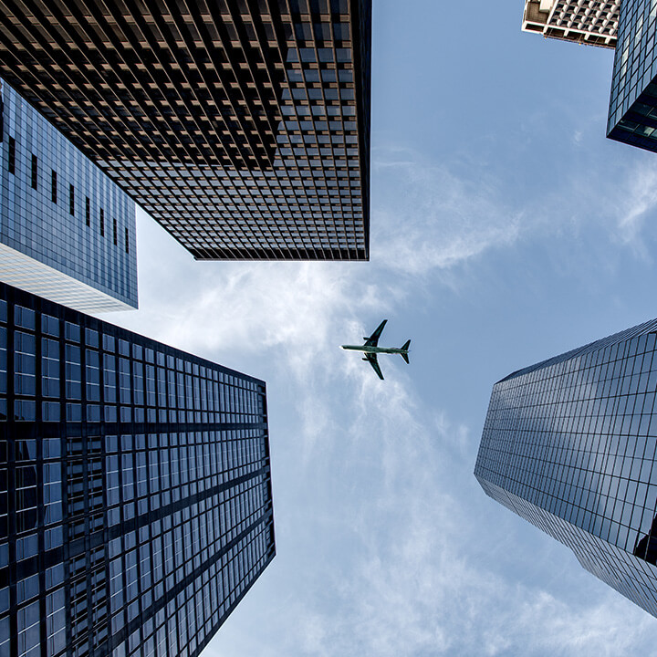 An image of a plane flying over a city scape. A visual metaphor for the topic of this content series on right-to-Work, the benefits of obtaining a sponsor licence