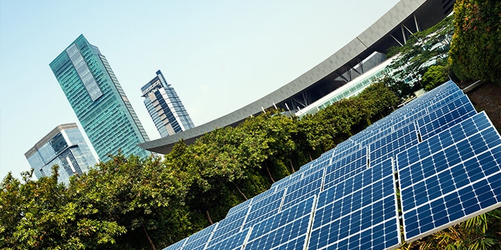 An image of a set of solar panels at a diagonal angle, with a building in the background. A visual metaphor for this post on ESG and environmental reporting.
