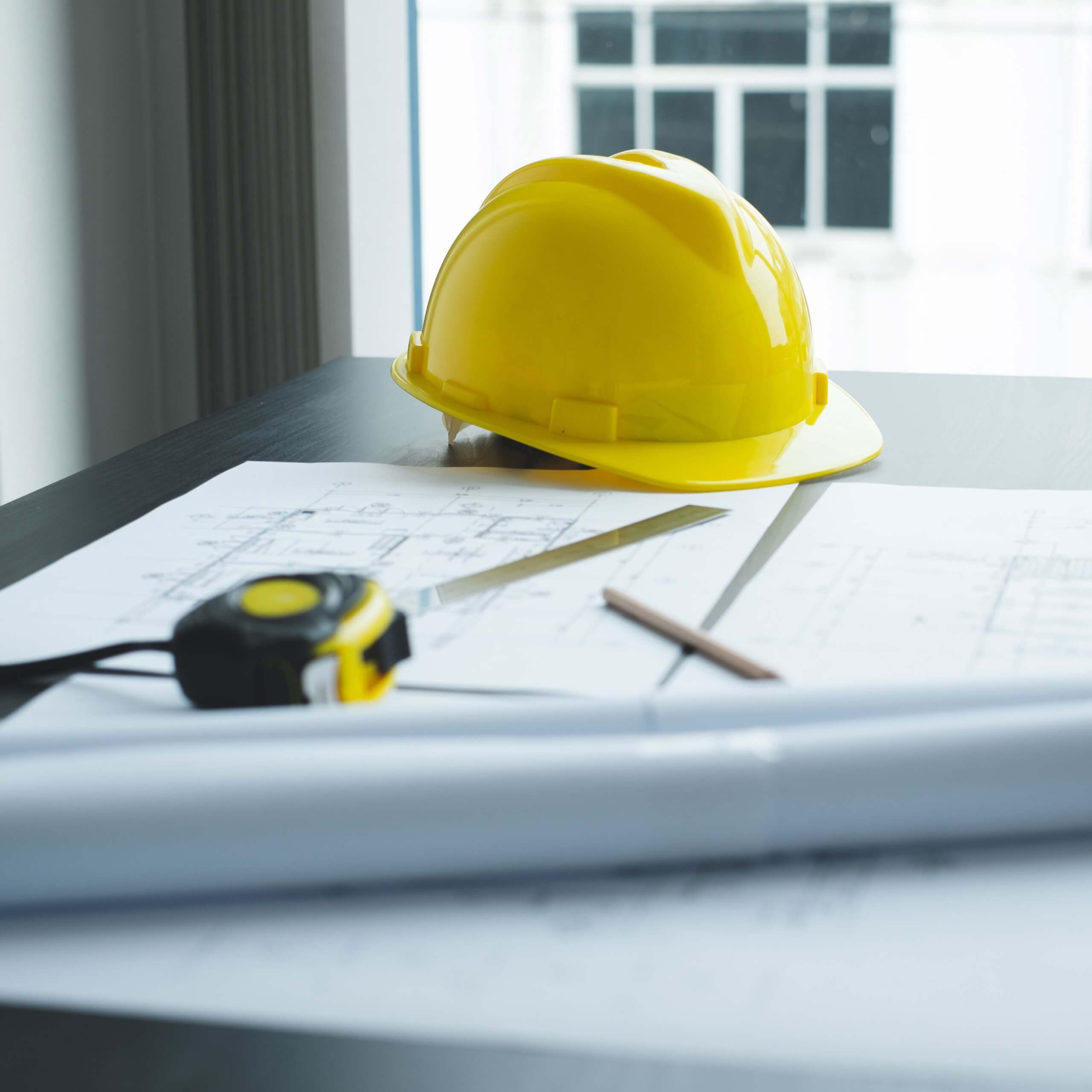 Safety helmet with measuring tape on documents from a building site.
