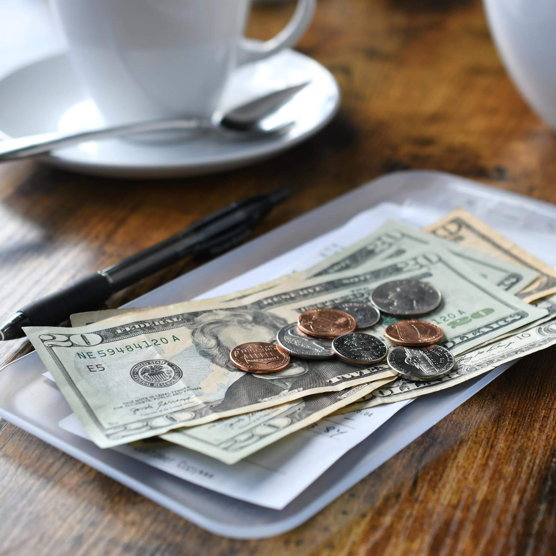 An image of a coffee table with money placed in a receiving tray. A visual metaphor for the topic of this article , the Employment (Allocation of Tips) Act 2024.
