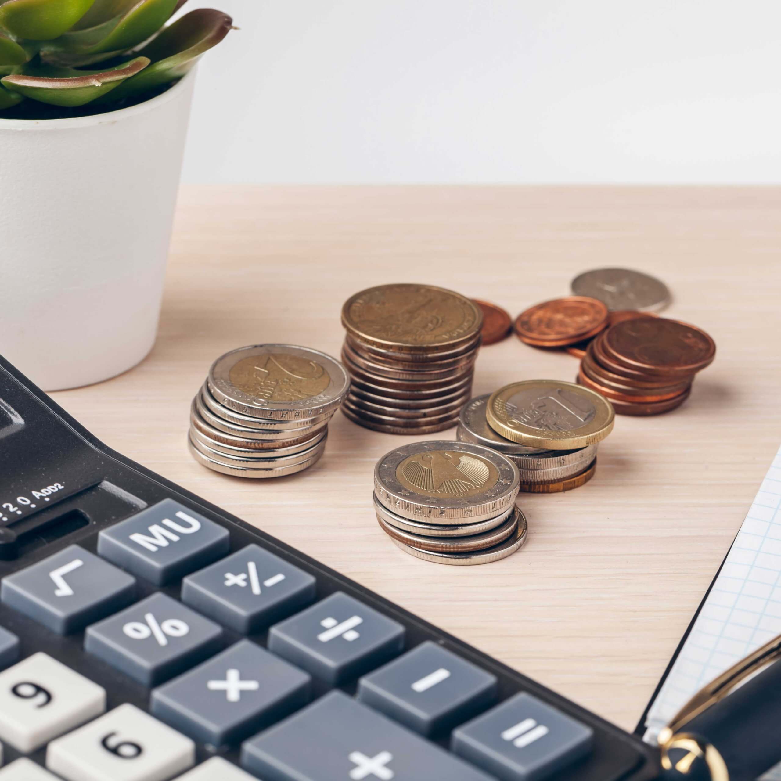 An image of a calculator, coins and p;art of a plant, all on a desk. A visual metaphor for the topic of this post, Financial promotion exemptions: Government U-turn.