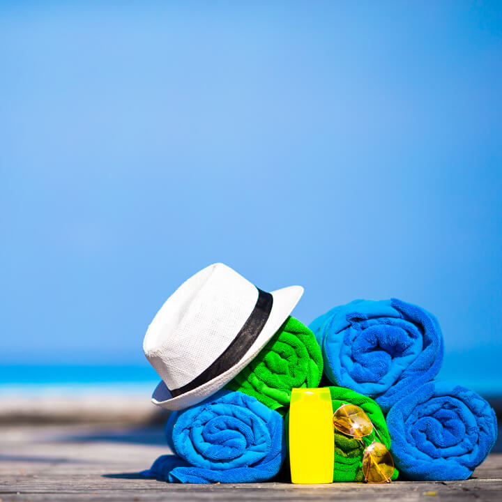 An image of various towels and holiday items on a beach with the sea in the background. A visual metaphor for the topic of this article, Changes to holiday pay