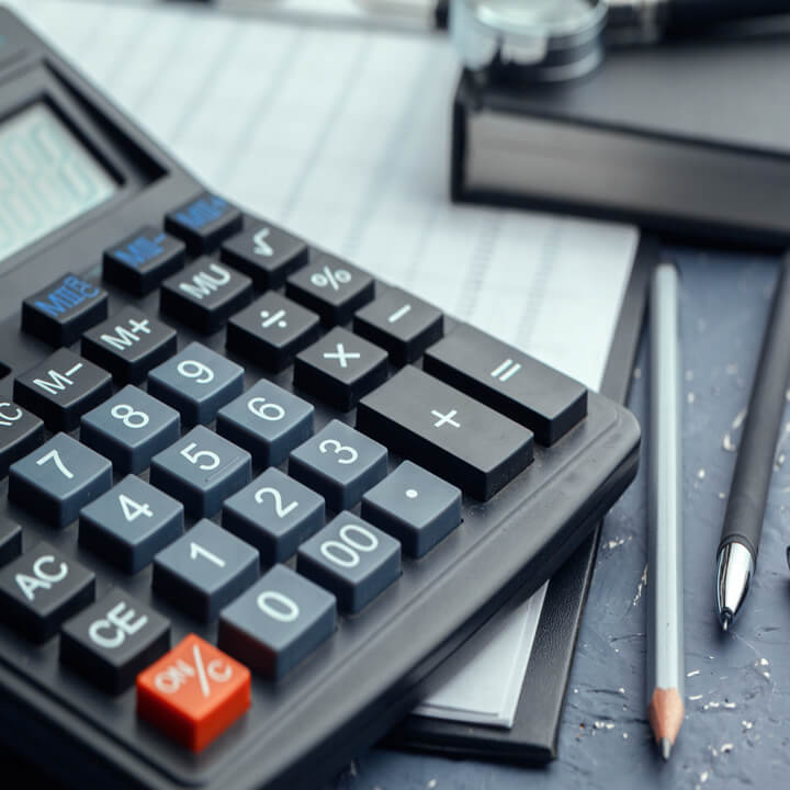 An image of a calculator sat on a desk with various utensils. A visual metaphor for the topic of this article, Re-introduction of fees in the Employment Tribunals and the EAT?