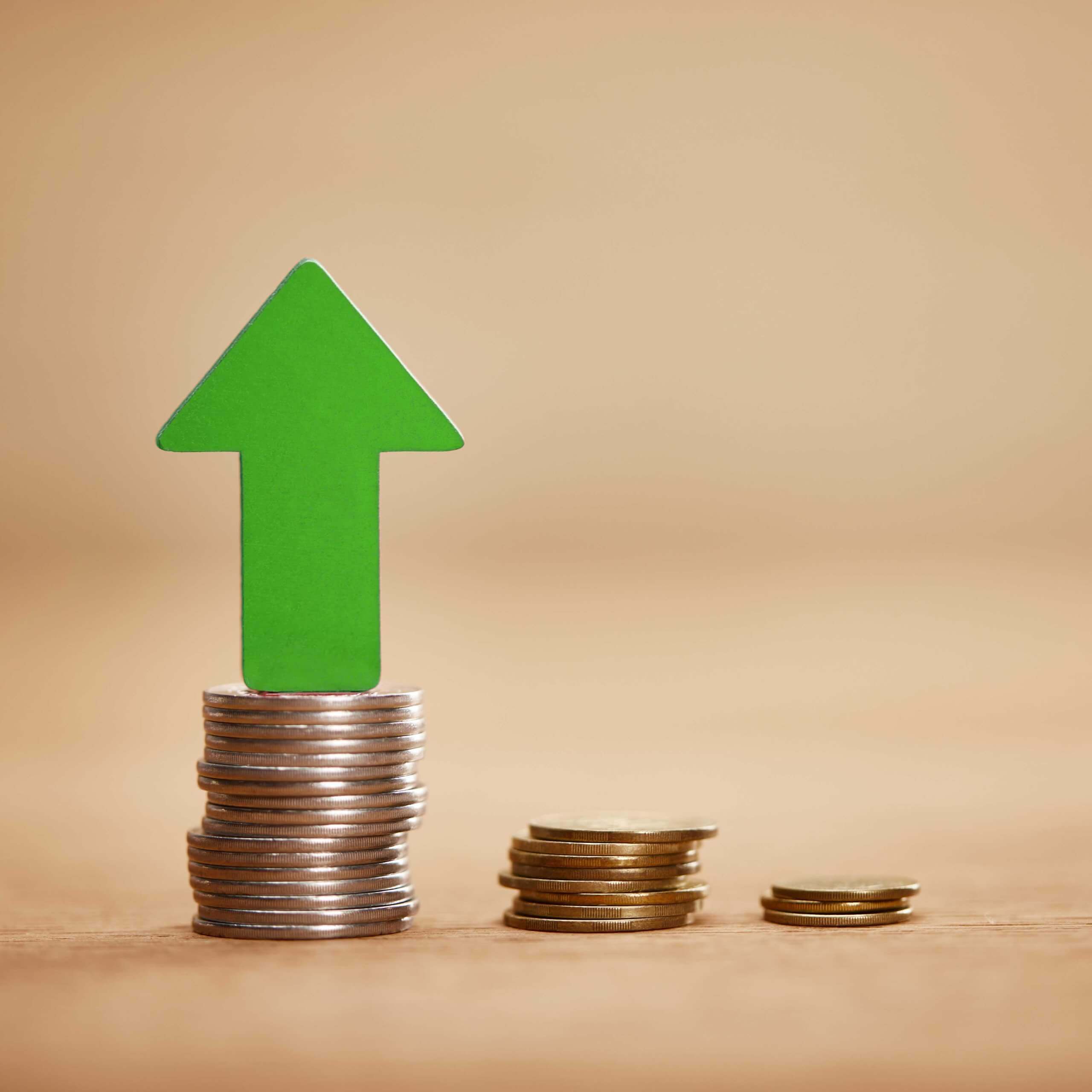 An image of money on a table, with a green arrow signifying an increase. A visual metaphor for the topic of this article National Minimum Wage increases from 1 April 2024